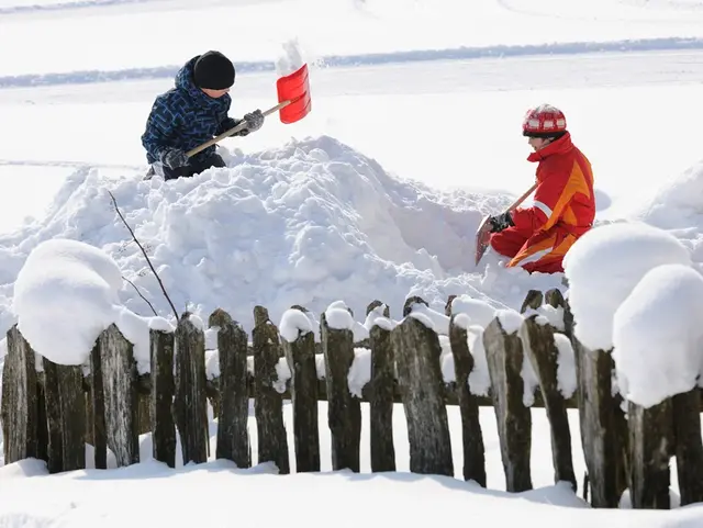 Kinder spielen und bauen Iglu im Winter auf dem Bauernhof am Chiemsee