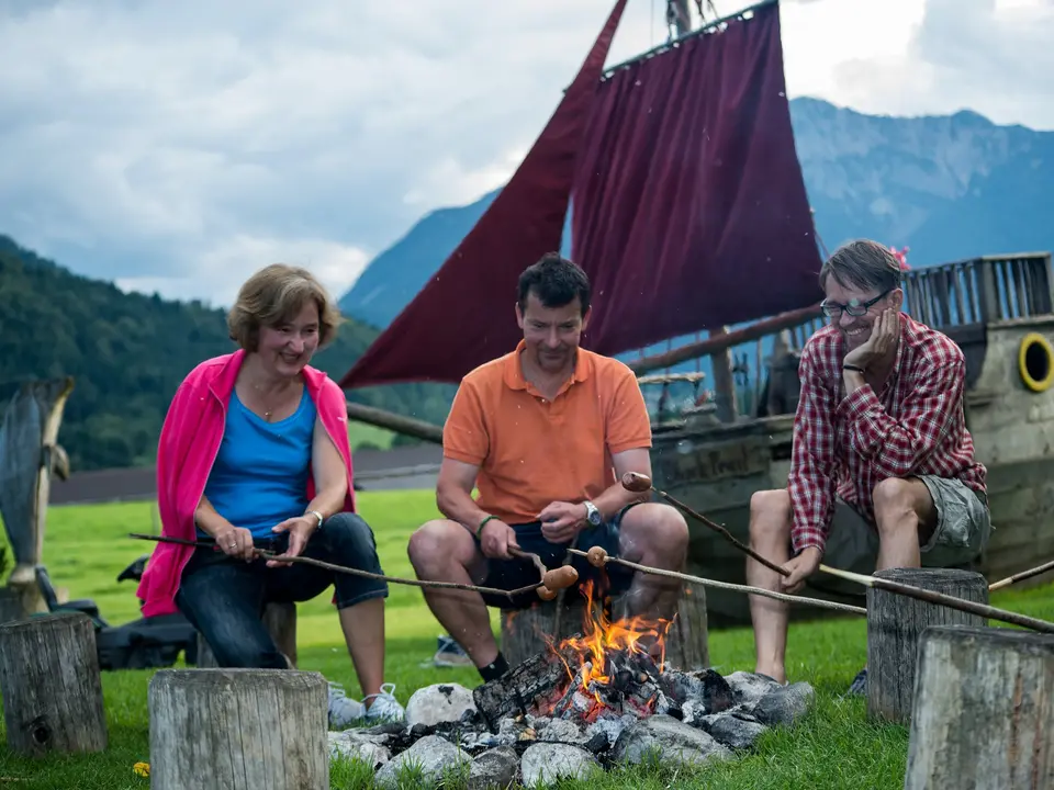 Erwachsene sitzen gemütlich am Lagerfeuer in einer Runde