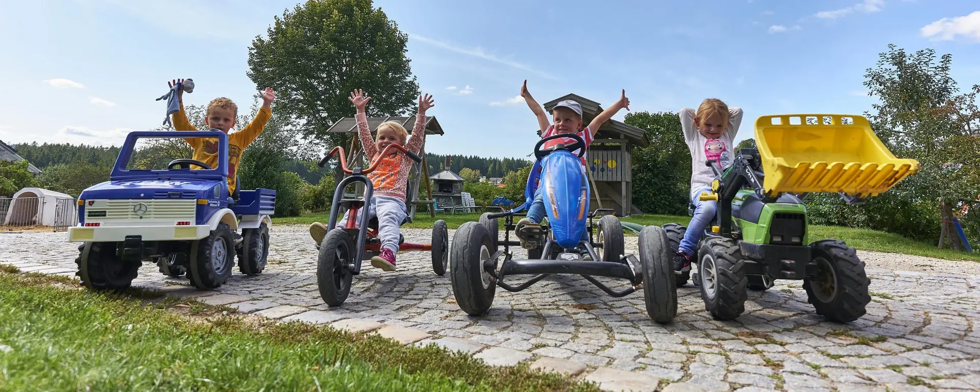 Auf Tretfahrzeugen durch den Hof auf dem Kinderbauernhof