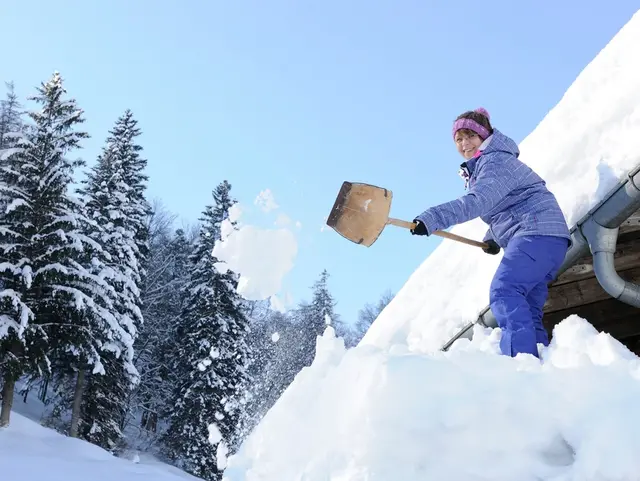 Schneeschaufeln im Winter auf dem Bauernhof am Chiemsee