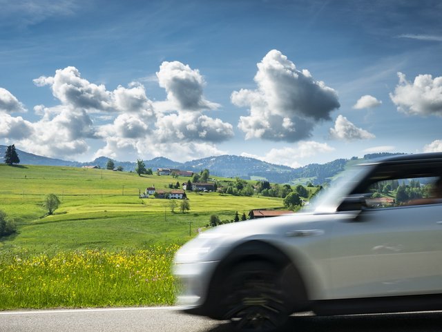 Fahrender weißer Mini vor Alpenpanorama auf der Deutschen Alpenstraße