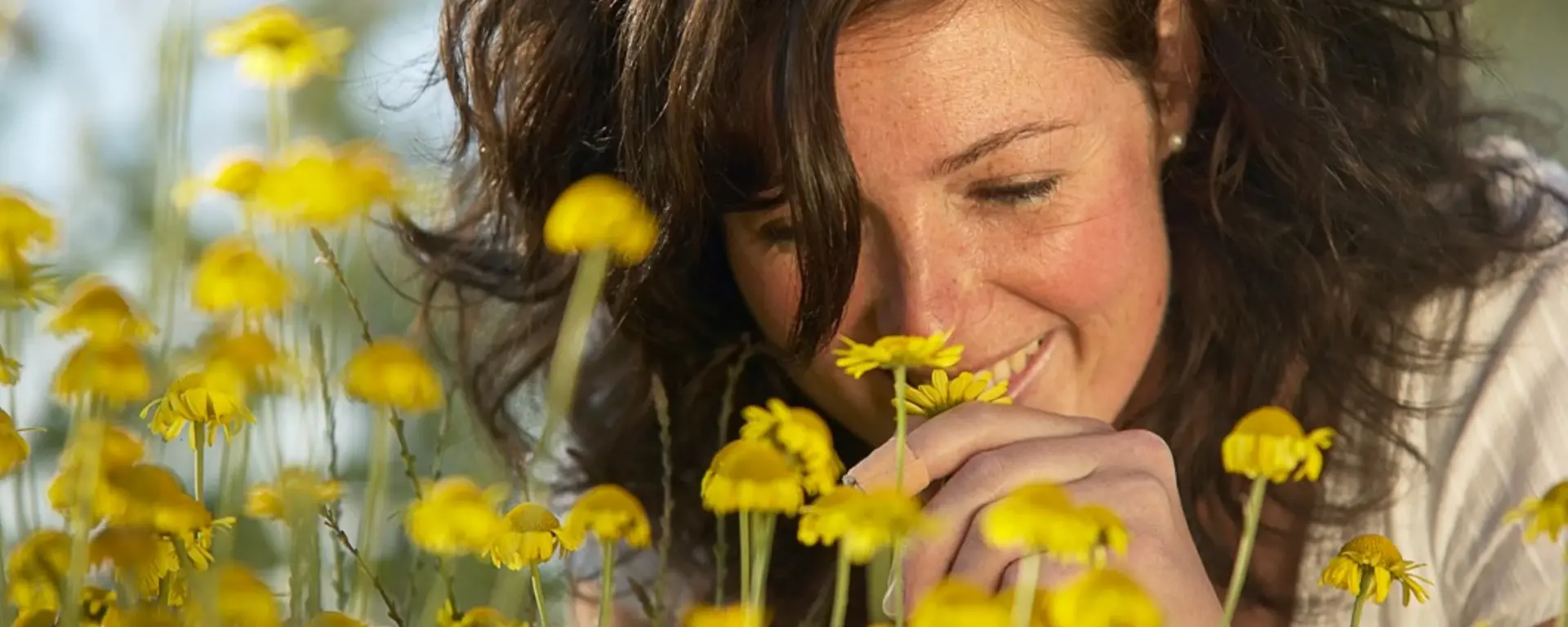 Frau schnuppert an Blumen