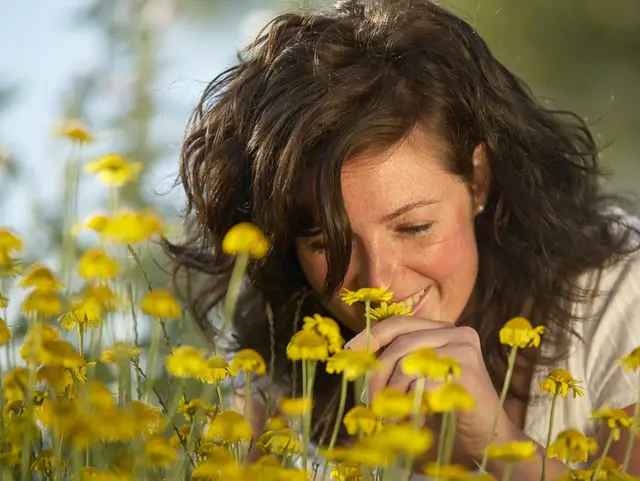 Frau schnuppert an Blumen